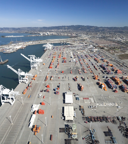 Aerial view of port with cargo and adjacent waterway on a clear day.