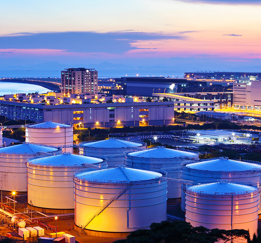 Aerial view of industrial liquid tanks during sunset.