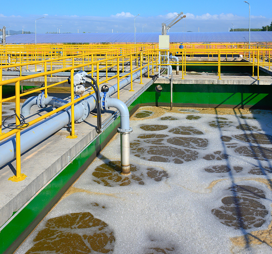 Wastewater treatment plant with yellow guardrails over treatment basins