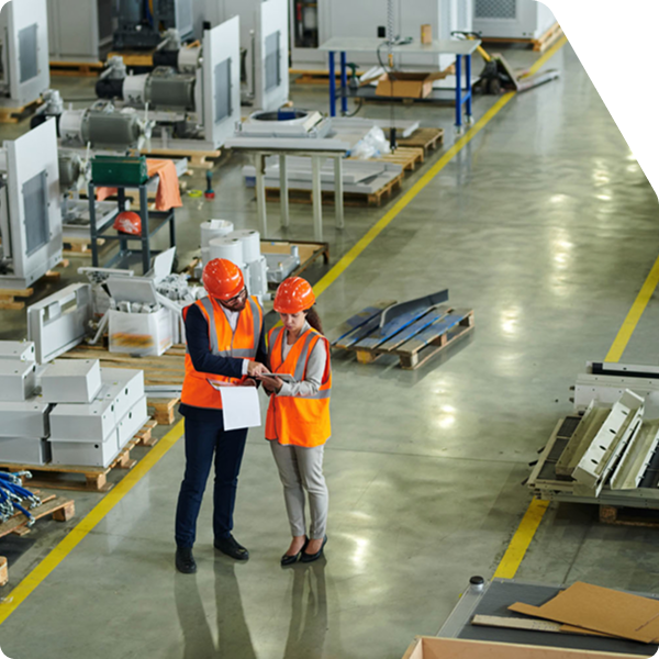 Two workers looking at compliance documentation inside a commercial manufacturing facility.