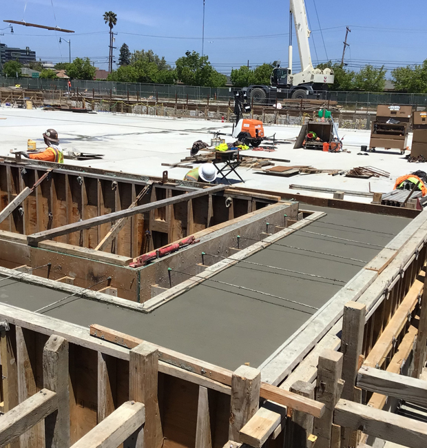 Construction workers constructing a building with blue sky in background.