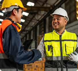 Engineer and clients shaking hands in an industrial facility.